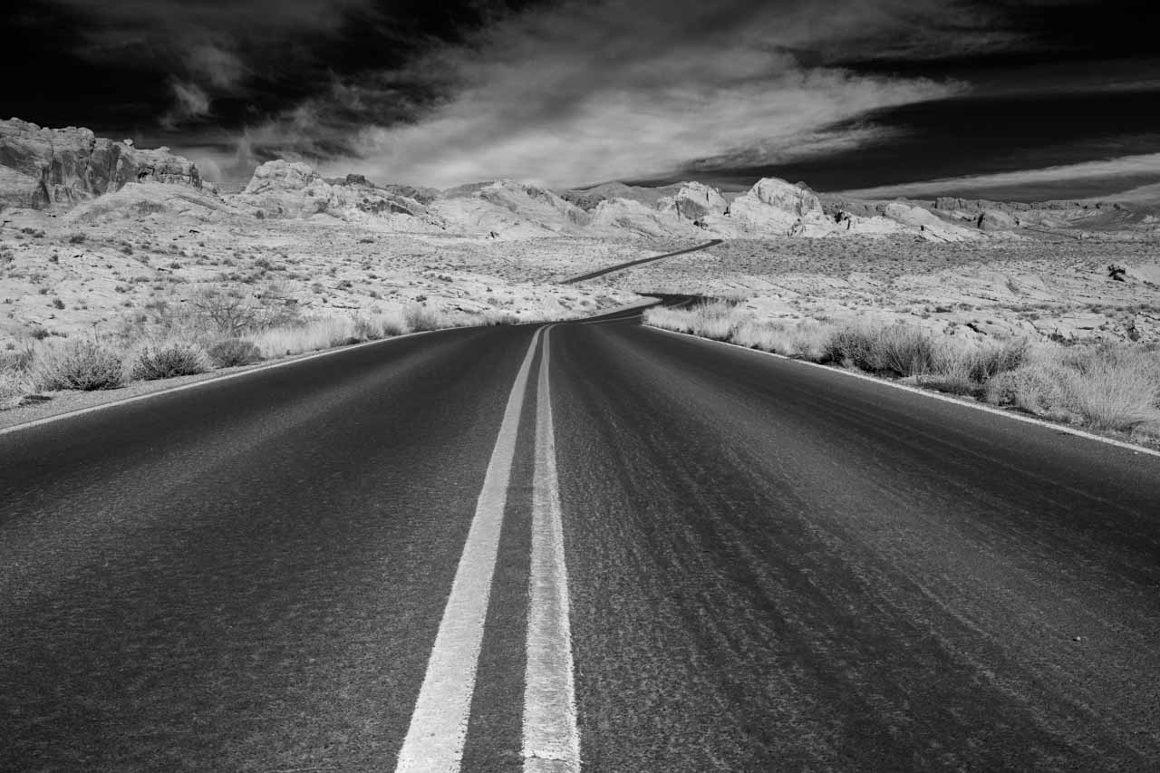 Photo en noir et blanc de la route qui mène vers Valley of Fire dans le Nevada. Photographie par Amar Guillen, artiste photographe.
