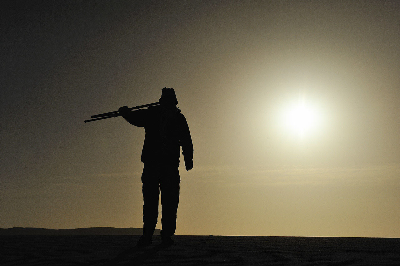 Amar Guillen, photographe, marchant dans le désert au crépuscule.