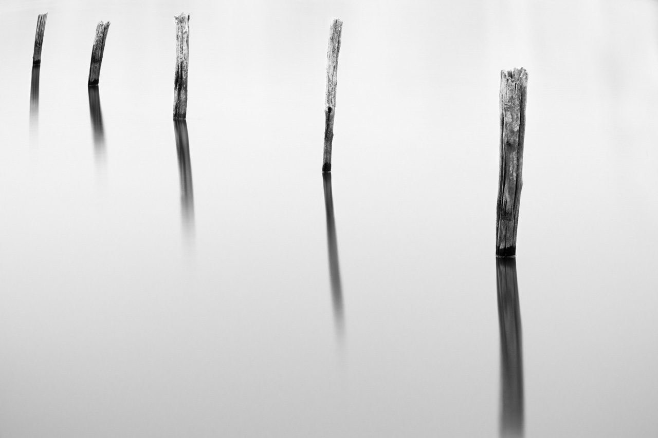 Photographie conceptuelle réalisée sur un étang. Piquets photographiés en pose longue.