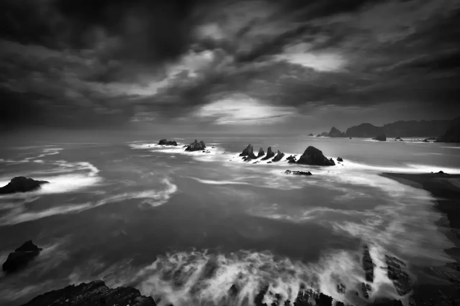 Seascape of Asturias in Spain in black and white.The waves of the Atlantic Oceans break on the rocks of the shore or on the cliffs.