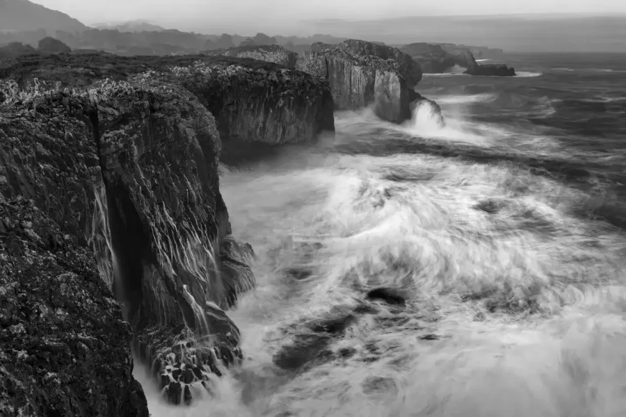 Seascape of Asturias in Spain in black and white.The waves of the Atlantic Oceans break on the rocks of the shore or on the cliffs.