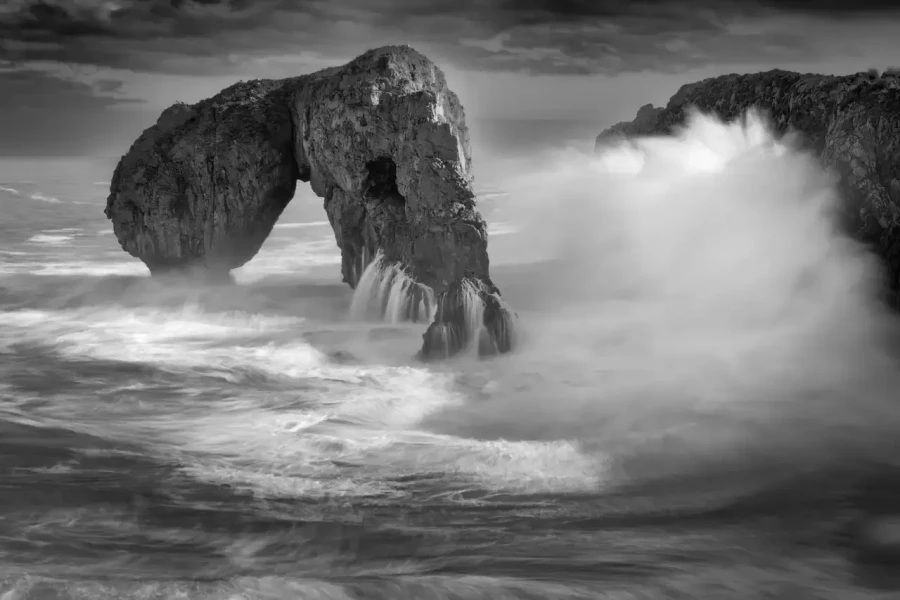 Seascape of Asturias in Spain in black and white.The waves of the Atlantic Oceans break on the rocks of the shore or on the cliffs.