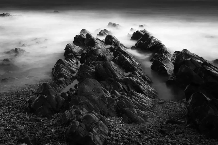 Seascape of Asturias in Spain in black and white.The waves of the Atlantic Oceans break on the rocks of the shore or on the cliffs.