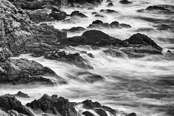 Vagues s'écrasant sur des rochers sur la côte du finistère sud en Bretagne en France. Photographie d'art en noir et blanc par Amar Guillen, artiste photographe.